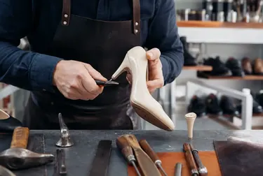 Sapateiro fazendo a troca de salto em um sapato, com materiais e ferramentas de qualidade.