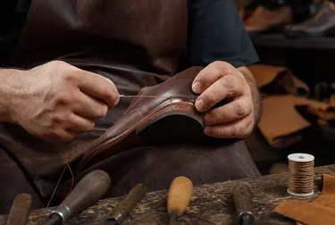 Sapateiro utilizando uma máquina de costura para reparar um calçado danificado.